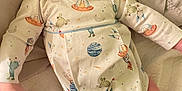 Grayson is registered to the contest to win money with this photo: baby, infant, onesie, space_theme, hand, tattoo, quilt, bed, cute, child, skin, face, looking, comfort, resting, indoor, human, person, clothing, newborn