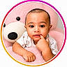 baby, child, teddy_bear, pink, cute, portrait, indoor, soft_toy, hand, face, young, childhood, smiling, looking_at_camera, clothing, infant, circular_frame, furniture, plush, expression