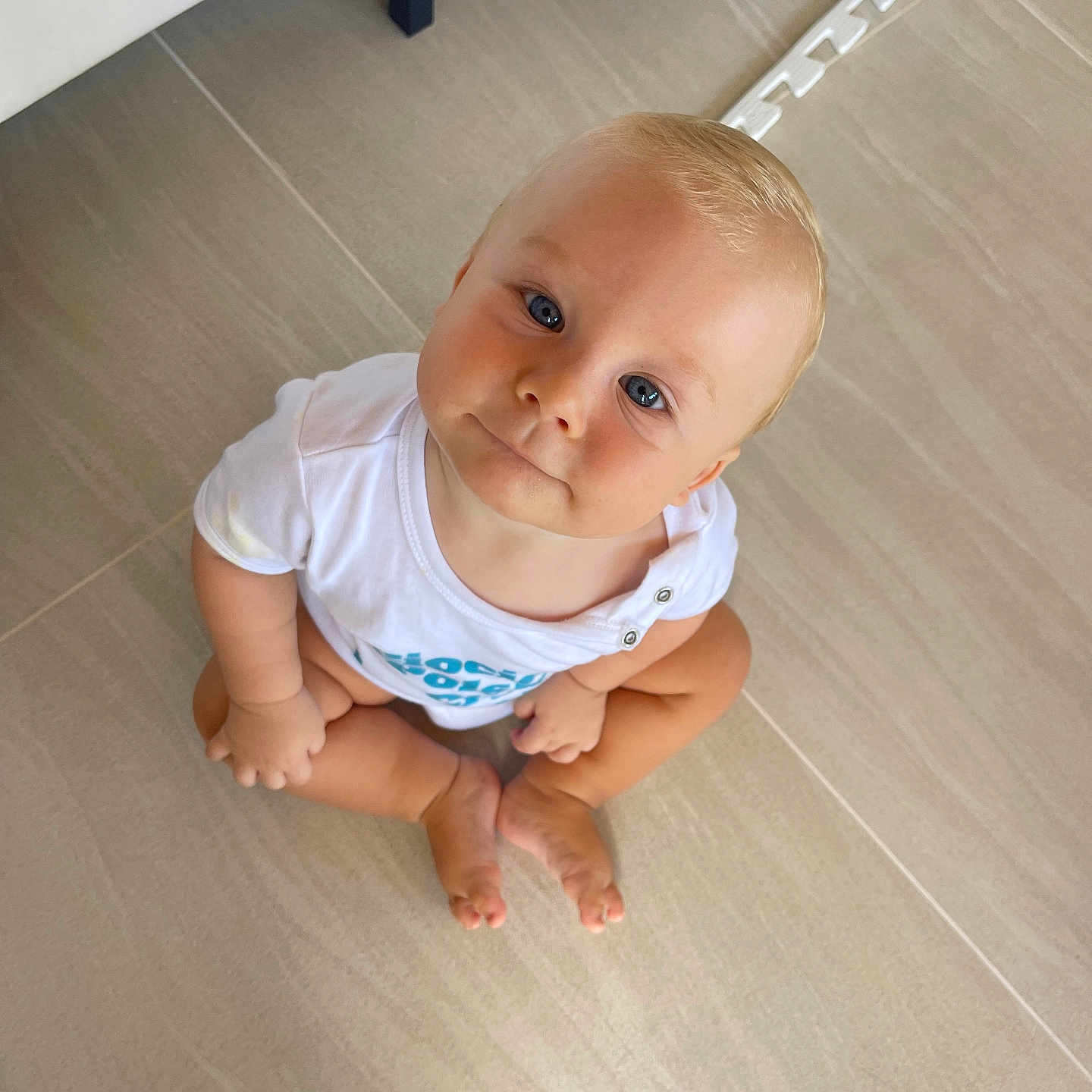 Mieszko joined the competition — help win amazing prizes! baby, barefoot, blue_eyes, child, curious, cute, face, floor, head, indoor, looking_up, minimalist, person, portrait, sitting, skin, tile_floor, toddler, white_shirt, young_child