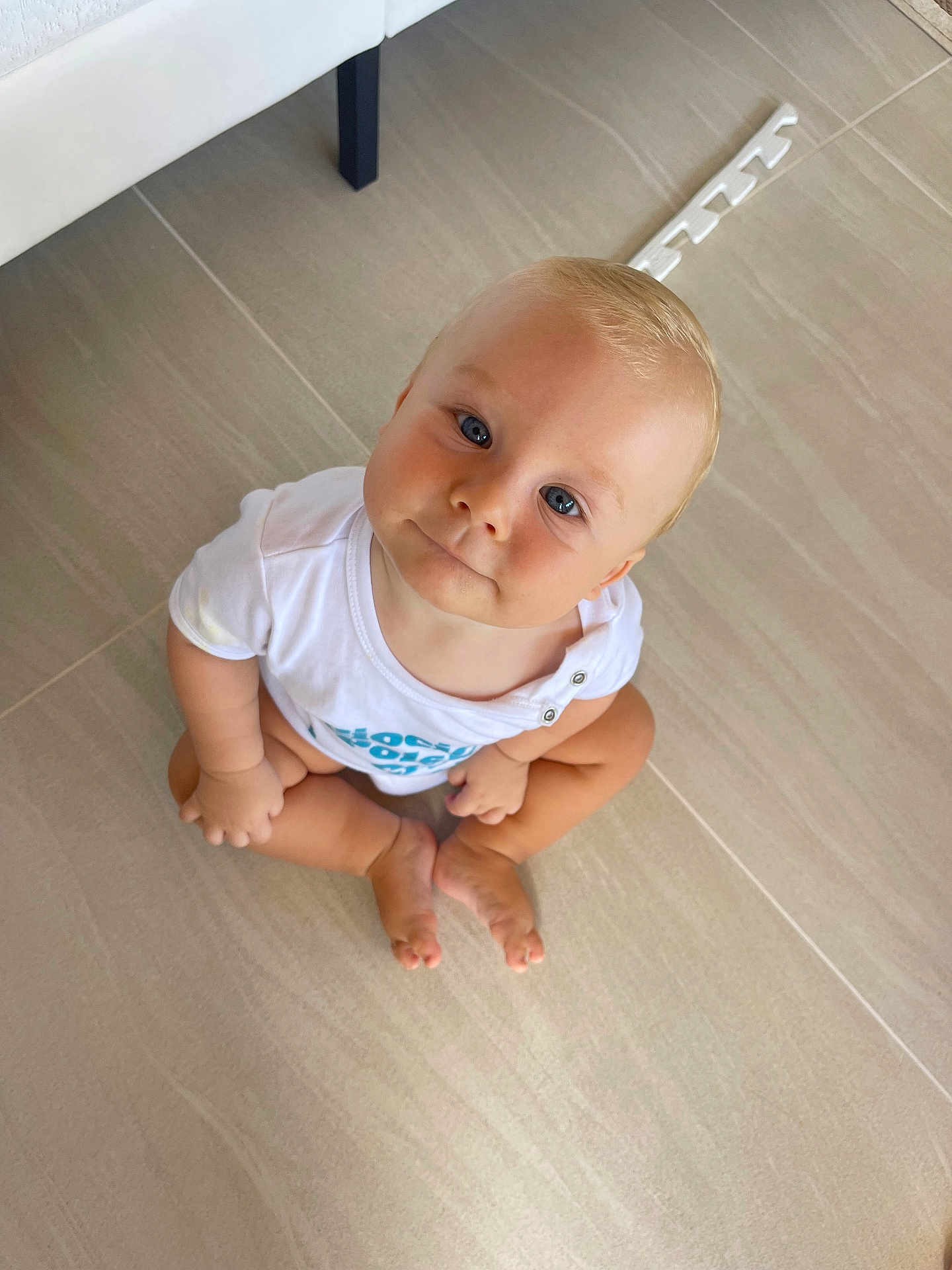 Mieszko joined the competition — help win amazing prizes! baby, barefoot, blue_eyes, child, curious, cute, face, floor, head, indoor, looking_up, minimalist, person, portrait, sitting, skin, tile_floor, toddler, white_shirt, young_child