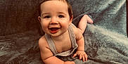 Greyson joined the competition — help win amazing prizes! baby, smiling, face, eyes, hands, skin, clothing, overalls, blanket, soft_texture, cute, infant, child, happy, lying_down, portrait, indoors, closeup, young, person