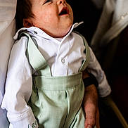 Leo joined the competition — help win amazing prizes! baby, infant, child, white_shirt, green_suspender, portrait, smiling, happy, cute, person, human_hand, closeup, fashion, clothing, young_child, indoor, soft_lighting, gentle, care, love