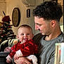 baby, child, man, smiling, indoor, christmas_tree, holiday, red_clothing, velvet, portrait, family, holding, happy, festive, decoration, young_adult, home, table, furniture, celebration