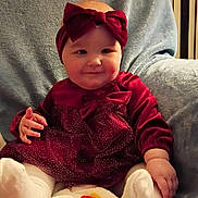 Paisley is registered to the contest to win money with this photo: baby, infant, dress, headband, maroon, sitting, blanket, chair, cozy, indoors, cute, smiling, happy, child, person, sock, holiday, halloween, decor, plush