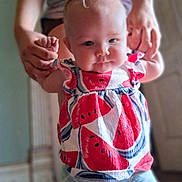 Lynsey is registered to the contest to win money with this photo: baby, child, infant, dress, watermelon_pattern, holding_hands, indoor, person, cute, face, skin, arms, closeup, smiling, young, human, apparel, colorful, portrait, happy