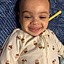 Ashure Matthews is registered to the contest to win money with this photo: baby, smiling, face, acorn_pattern, onesie, blanket, blue_blanket, infant, child, cute, happy, lying_down, cozy_clothing, portrait, indoor, skin, head, tongue_out, closeup, young_child