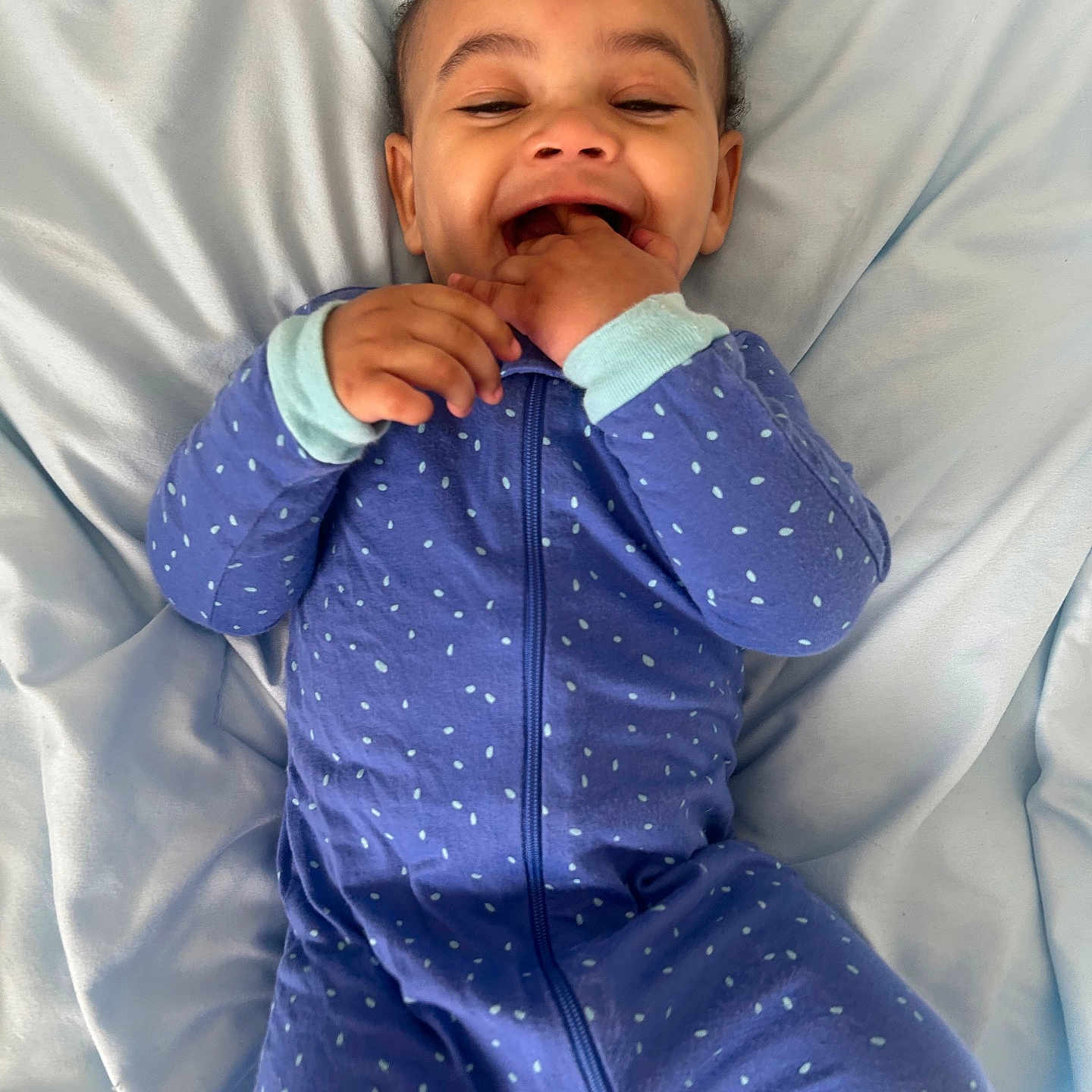 Ashure Matthews joined the competition — help win amazing prizes! baby, bed, blanket, blue_clothing, child, cute, face, fingers, hair, hands, happy, indoors, infant, lying_down, mouth, onesie, polka_dot, skin, smiling, soft