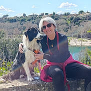 Nicky a rejoint le concours — aidez-le/la à gagner de superbes lots ! woman, dog, outdoor, nature, lake, trees, sky, clouds, stone_wall, harness, sunglasses, smiling, happy, pet, water, village, sunlight, leisure, casual, portrait