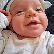 Everleigh joined the competition — help win amazing prizes! baby, newborn, infant, smiling, face, closeup, hat, onesie, hand, cheek, mouth, eyes, skin, blanket, bedding, cozy, happy, portrait, newborn_clothing, lying_down