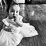 child, toddler, baby, floor, wood_floor, tutu, clothing, sitting, cute, portrait, indoor, black_and_white, hair, pony_tail, hand, face, curious, expression, home, furniture