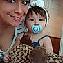 Piper is registered to the contest to win money with this photo: woman, toddler, pacifier, headband, plush_toy, indoor, smile, face, child, person, clock, door, hair, eyes, clothing, bedspread, toy, cute, family, portrait