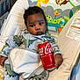 baby, infant, dinosaur_onesie, baby_rocker, coca_cola_can, jungle_animals, giraffe, sloth, toucan, toddler, cute, child, indoor, clothing, seat, toy_pattern, colorful, portrait, holding, drink_can