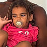 Soën participe au concours pour gagner de l'argent avec cette photo : adult_arm, braided_hair, candid, casual, child, closeup, comfort, diaper, expression, family, holding, indoor, pacifier, person, pink_shirt, portrait, seated, skin, toddler, young_child