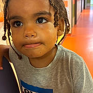 Soën participe au concours pour gagner de l'argent avec cette photo : braids, casual_clothing, child, closeup, curious, curly_hair, cute, expression, face, hair, hallway, indoor, levi's, orange_floor, person, portrait, skin, standing, tshirt, young