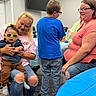 Elijah joined the competition — help win amazing prizes! baby, child, woman, glasses, indoor, chairs, table, people, casual_clothing, floor, smile, glasses_yellow, jeans, short_sleeve, holding, sitting, standing, person, room, family