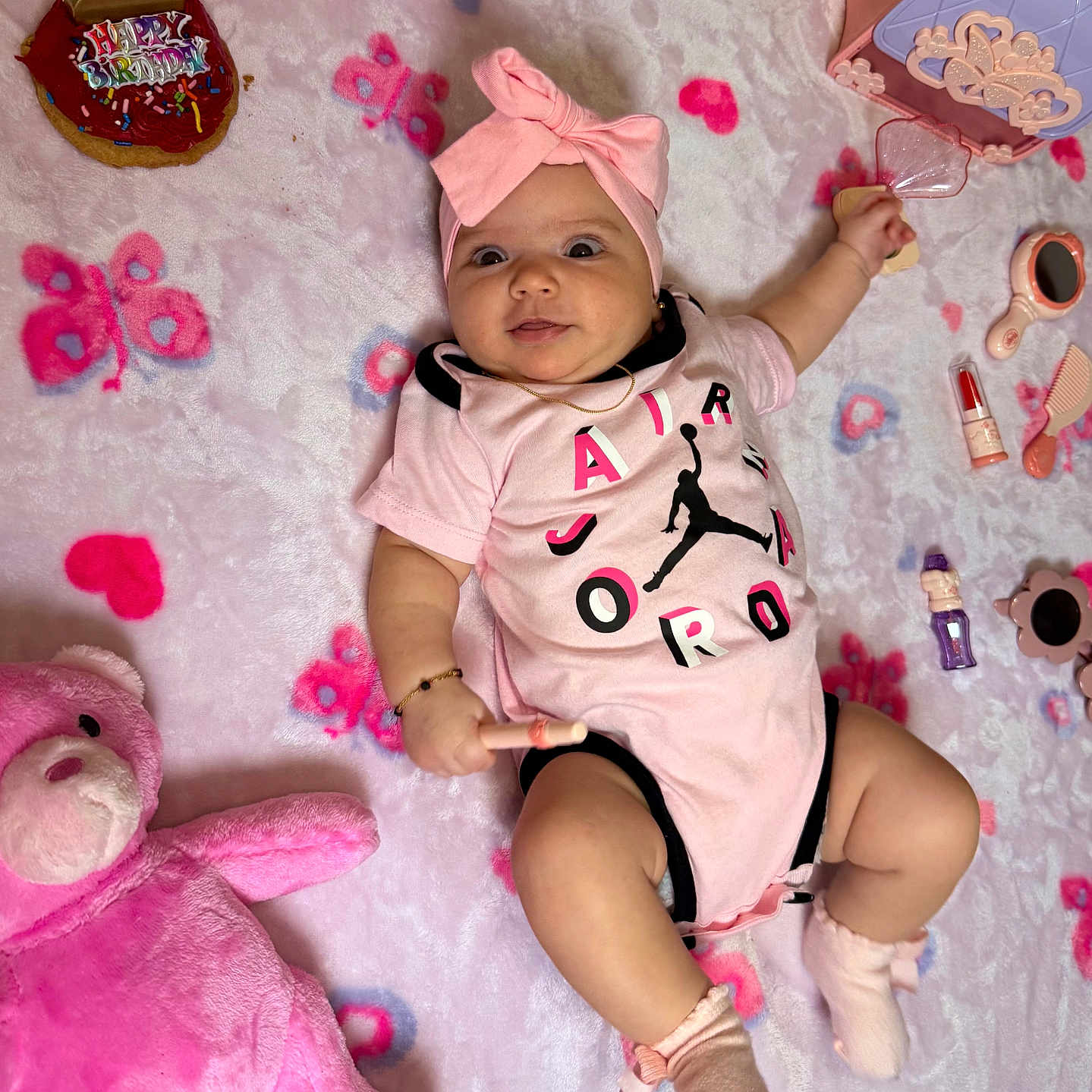 Fernanda is registered to the contest to win money with this photo: baby, birthday, blanket, butterfly_pattern, candle, cupcake, cute, face, girl, happy, headband, infant, laying, onesie, pink, play, smile, sock, stuffed_animal, toy