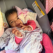 Aylani is registered to the contest to win money with this photo: baby, smiling, infant, car_seat, blanket, pink_clothing, cozy, hands, face, happy, cute, indoors, child, soft_texture, bottle, seatbelt, portrait, newborn, resting, warm