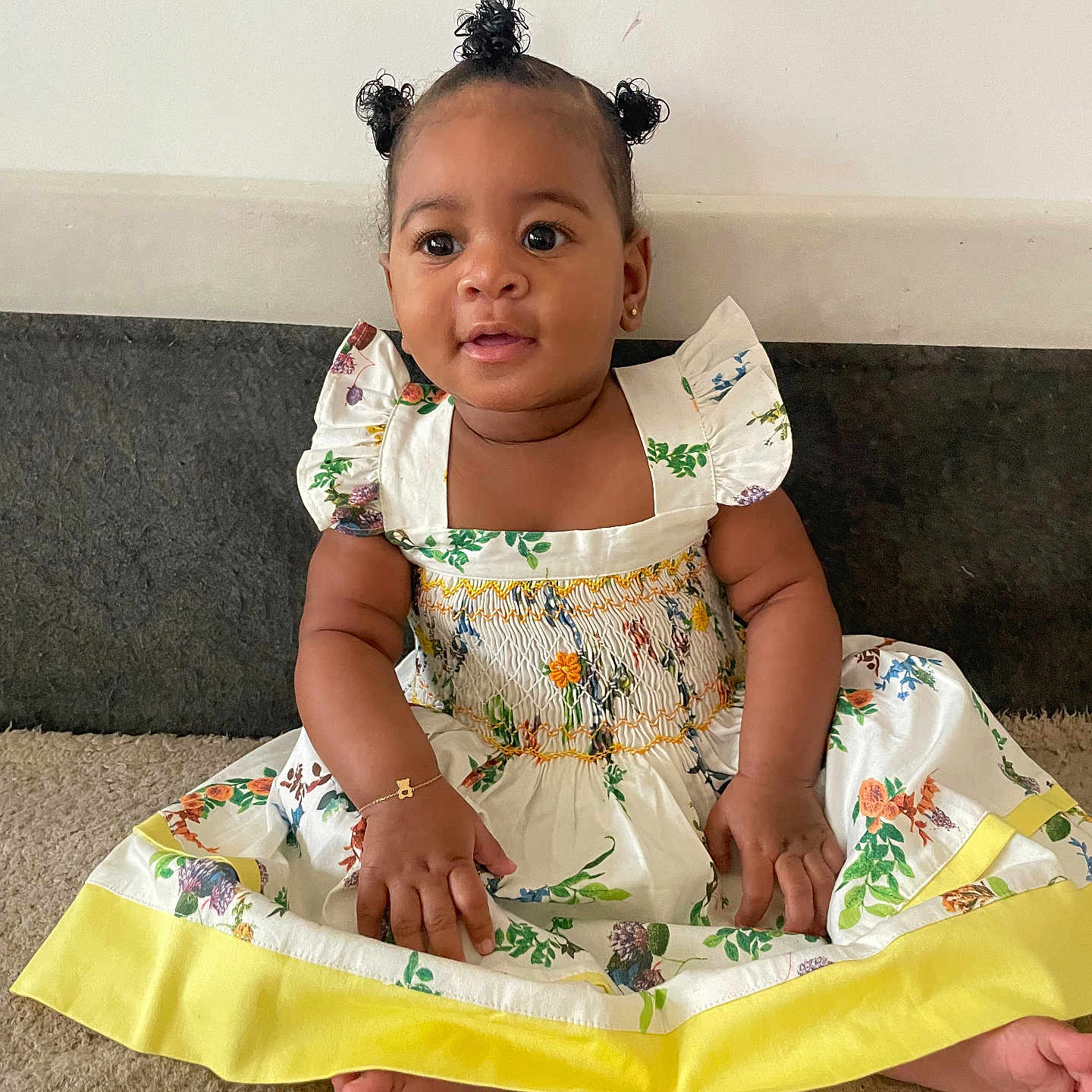 May participe au concours pour gagner de l'argent avec cette photo : adorable, baby, bracelet, carpet, child, cute, dress, fingers, floral, hair_buns, happy, indoor, infant, person, portrait, sitting, skin, smiling, toes, young