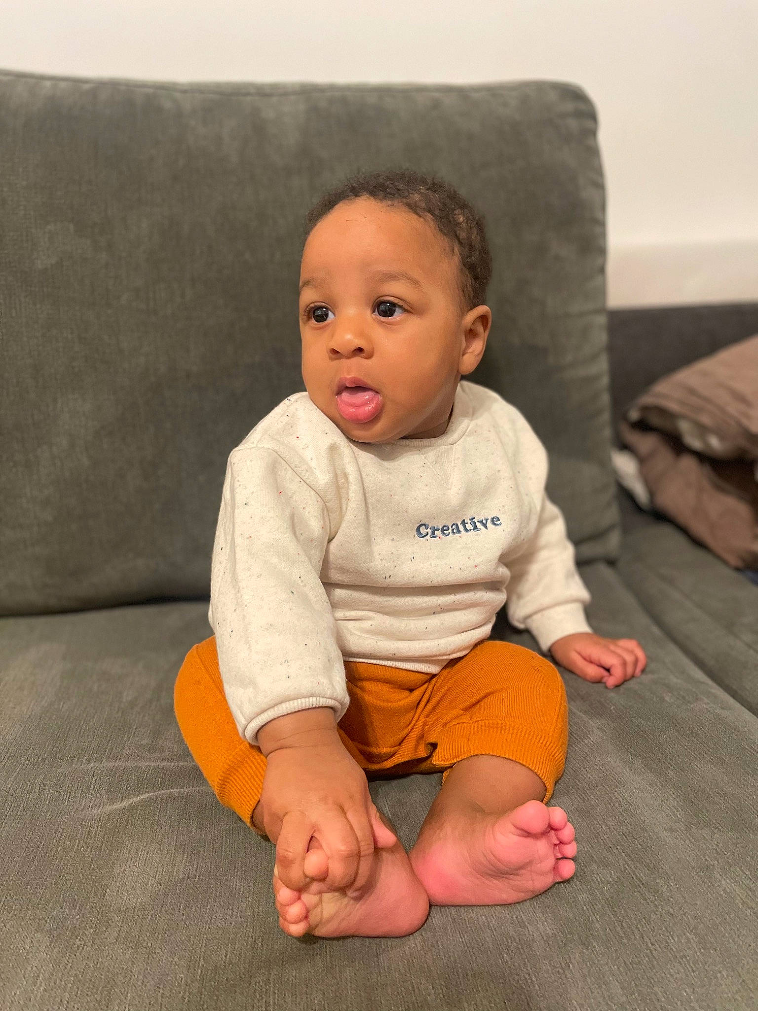 Neyji participe au concours pour gagner de l'argent avec cette photo : arm, baby, baby_toddler_clothing, cheek, child, comfort, couch, eye, face, floor, flooring, head, human_body, knee, leg, nose, person, skin, sleeve, surprise