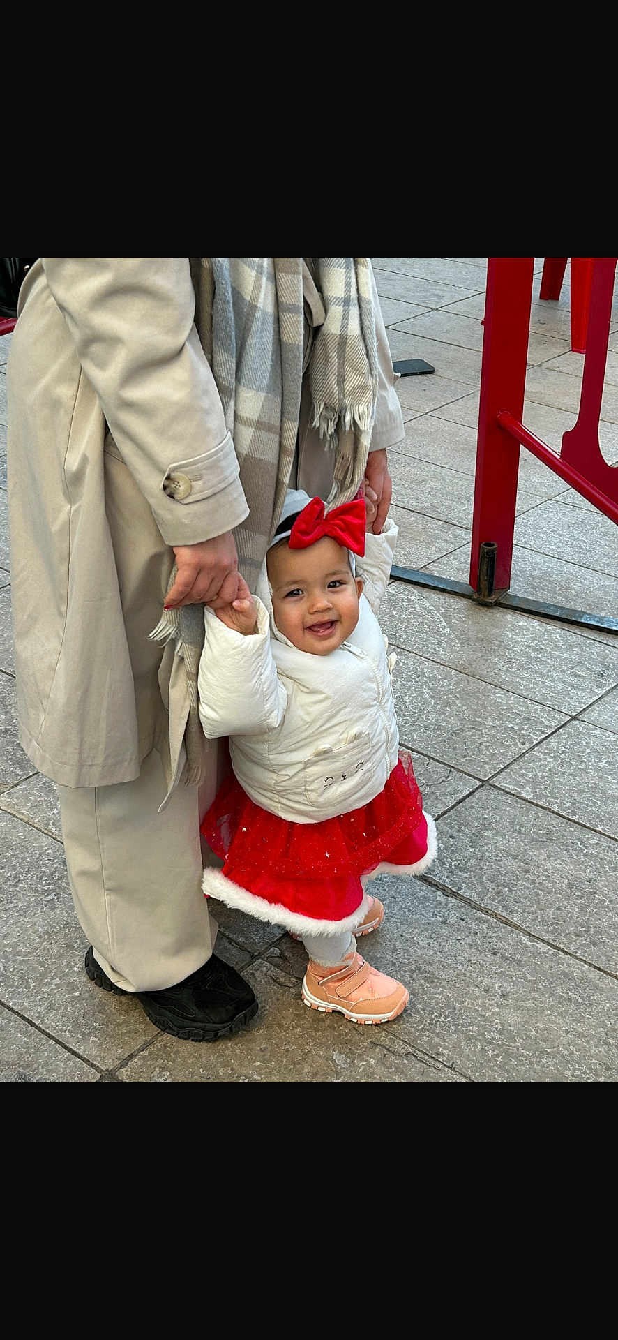 Aliyah participe au concours pour gagner de l'argent avec cette photo : toddler, child, adult, holding_hands, red_bow, red_skirt, white_jacket, scarf, sidewalk, outdoor, footwear, happy, walking, person, pavement, winter_clothing, smiling, urban, family, support