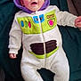 baby, bonnet, cap, clothing, coat, couch, face, hat, head, hood, hoodie, jacket, knitwear, pants, person, photography, portrait, purple, sweater, sweatshirt