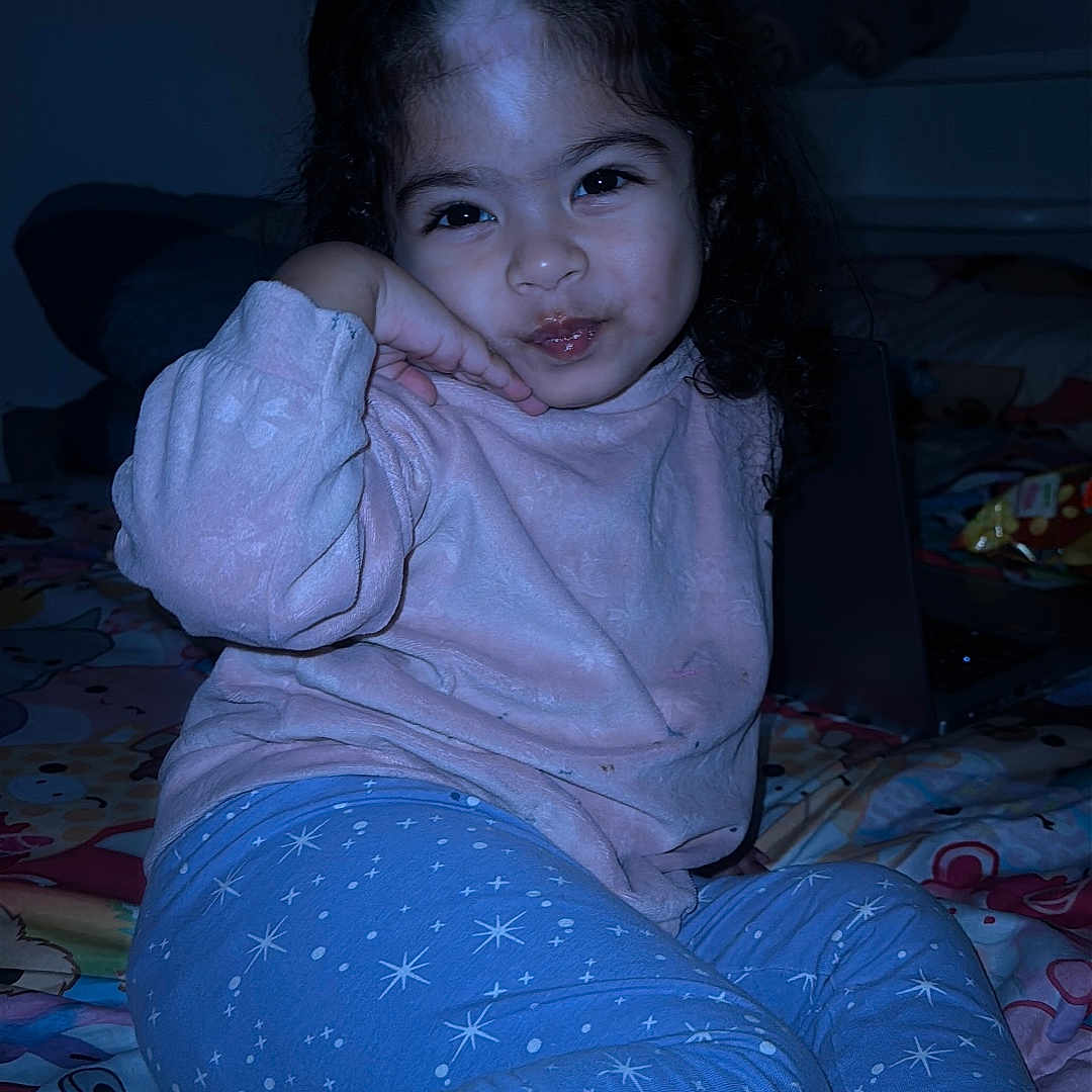 Júlia Saiume joined the competition — help win amazing prizes! bed, bedspread, child, cozy, curly_hair, cute, dark, girl, hand_on_cheek, indoor, laptop, nighttime, pajamas, person, playful, portrait, room, smiling, socks, toy