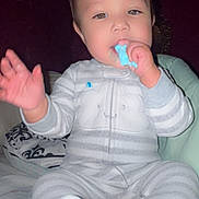 Christian joined the competition — help win amazing prizes! baby, child, pajamas, striped_clothing, bed, indoor, person, face, hand, sitting, cute, snack, chewing, blue_food, infant, young_child, cozy, sleepwear, smiling, portrait