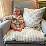 Weston is registered to the contest to win money with this photo: baby, smiling, armchair, blanket, cushion, wooden_sign, nine_months, sweater, happy, infant, indoor, cozy, child, feet, face, home, milestone, portrait, person, warm_lighting