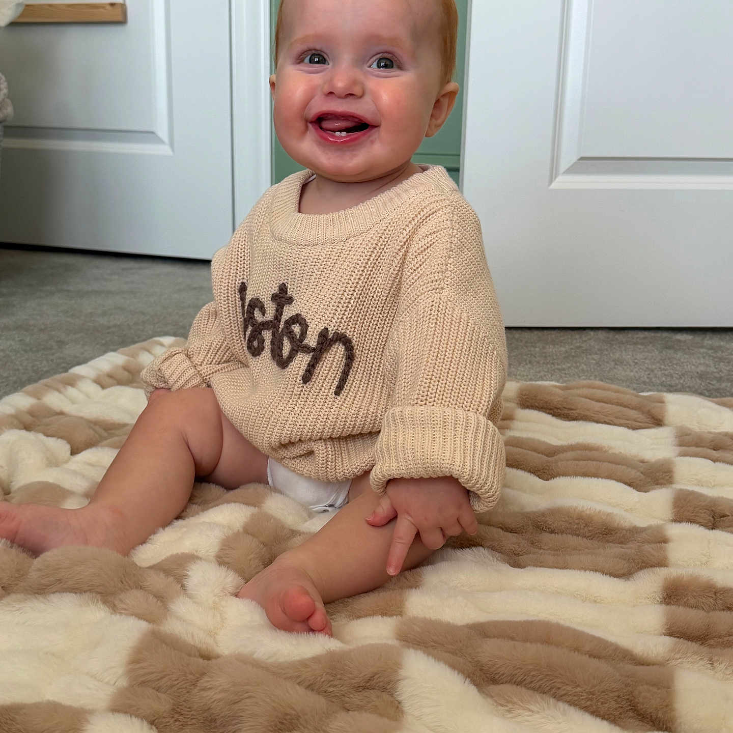 Weston is registered to the contest to win money with this photo: baby, smiling, sweater, blanket, indoor, child, happy, couch, plush, carpet, door, portrait, cute, infant, person, home, cozy, furniture, floor, animal_poster
