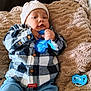 baby, blanket, blue_teething_toy, buttoned_shirt, casual, child, clothing, cozy, cute, face, hands, indoor, infant, jeans, knit_hat, lying_down, pacifier, plaid_shirt, portrait, soft_texture