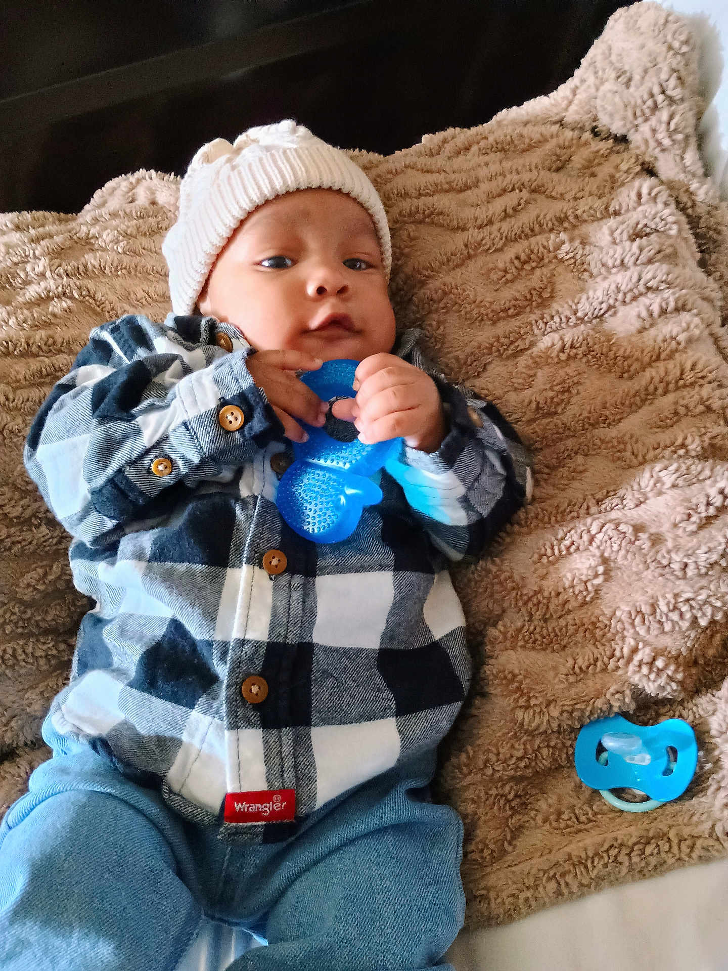 Khilan Lucas is registered to the contest to win money with this photo: baby, blanket, blue_teething_toy, buttoned_shirt, casual, child, clothing, cozy, cute, face, hands, indoor, infant, jeans, knit_hat, lying_down, pacifier, plaid_shirt, portrait, soft_texture