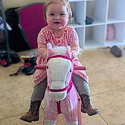 Melody is registered to the contest to win money with this photo: toddler, child, indoor, toy, rocking_horse, pink, plush, cowboy_boots, pigtails, smiling, floor_tiles, playroom, furniture, shelf, clothing, person, happy, cute, baby, floor