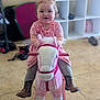 toddler, child, indoor, toy, rocking_horse, pink, plush, cowboy_boots, pigtails, smiling, floor_tiles, playroom, furniture, shelf, clothing, person, happy, cute, baby, floor