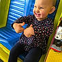 toddler, child, smiling, thumbs_up, playground, ride, colorful, blue_seat, yellow, floral_clothing, happy, cute, fun, outdoor, play, young_child, person, casual, joyful, expression