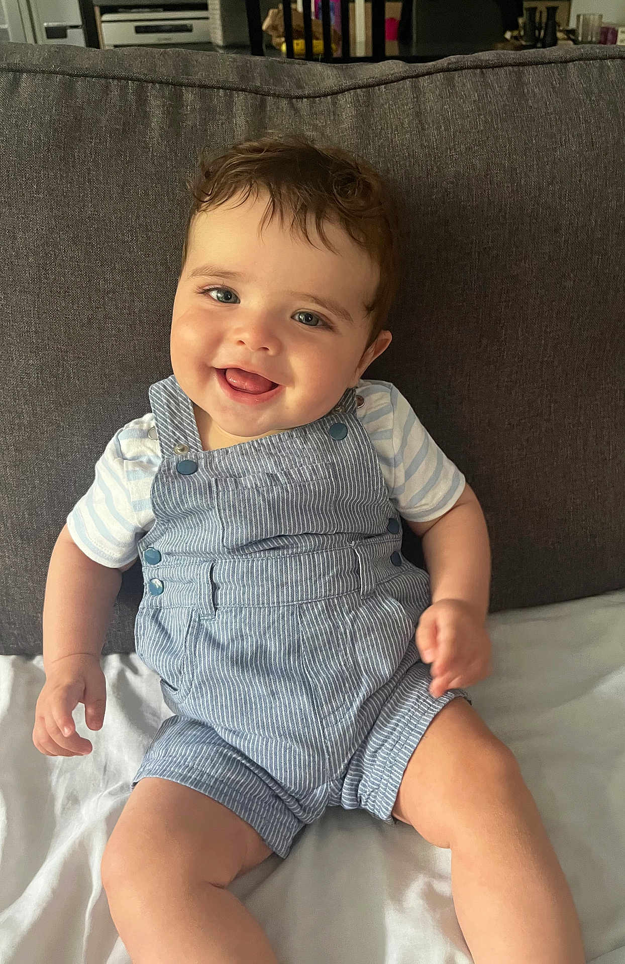 Mathys a rejoint le concours — aidez-le/la à gagner de superbes lots ! baby, child, smiling, overalls, striped_clothing, couch, cushion, indoor, happy, cute, face, person, sitting, infant, young_child, light_skin, short_hair, portrait, casual_clothing, relaxed