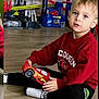 William a rejoint le concours — aidez-le/la à gagner de superbes lots ! black_pants, blonde_hair, blue_eyes, boy, candid, child, floorplay, hands, indoor, lightning_mcqueen, plastic_toy, playroom, portrait, red_sweater, sitting, toddler, toy_car, toy_racetrack, white_socks, wooden_floor
