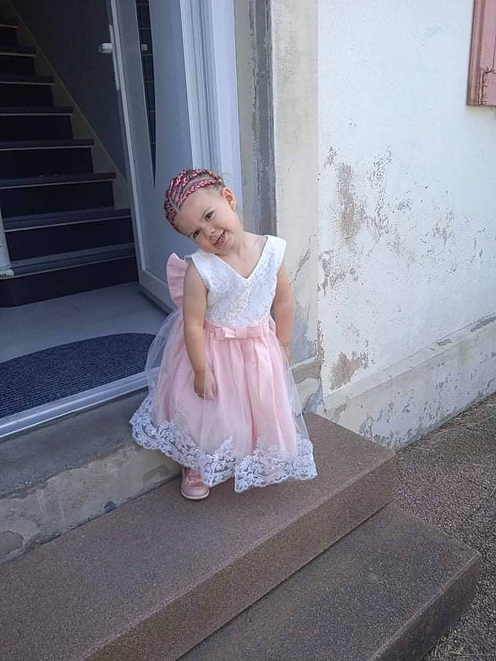 Yaelle a rejoint le concours — aidez-le/la à gagner de superbes lots ! bridal_accessory, child, day_dress, dress, embellishment, fashion_design, flash_photography, flooring, happy, headwear, human_leg, joy, knee, leg, one_piece_garment, person, ruffle, shoulder, skin, stairs