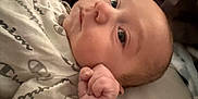 Brandon joined the competition — help win amazing prizes! baby, infant, face, hand, fist, clothing, indoor, person, cute, newborn, sleeping_surface, patterned_clothing, skin, head, eyes, expression, resting, closeup, soft, young_child