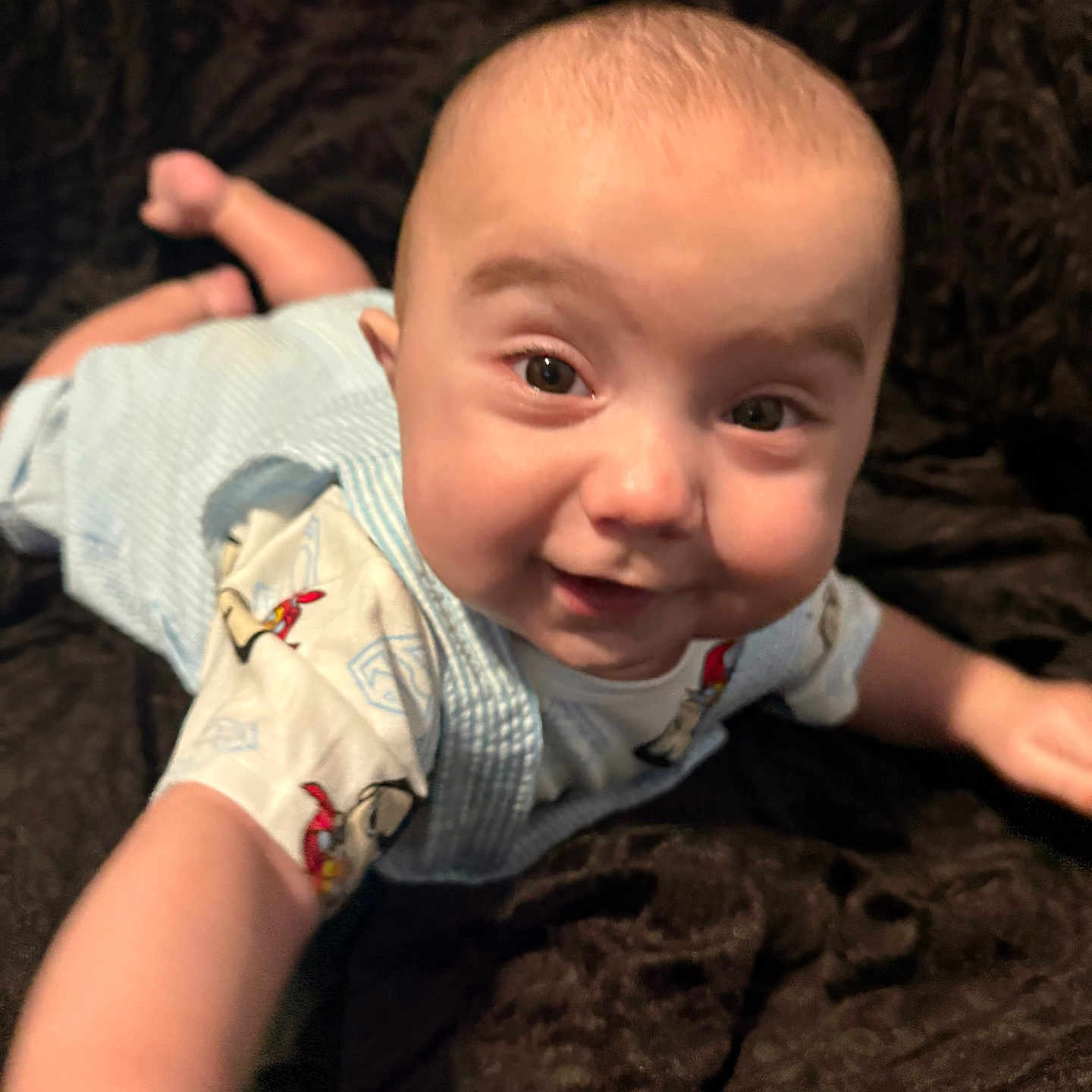 Brandon joined the competition — help win amazing prizes! arm, baby, blanket, cartoon_print, child, clothing, cute, face, head, indoor, infant, light_blue, pattern, person, playful, portrait, reaching, skin, smiling, young