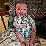 Brandon is registered to the contest to win money with this photo: baby, smile, infant, romper, blanket, chair, pattern, elephant_patch, happy, indoor, person, clothing, foot, hand, face, cute, seated, cozy, soft, warm_lighting