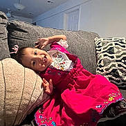 Daphne joined the competition — help win amazing prizes! toddler, child, smiling, dress, pink_dress, couch, pillow, indoor, happy, person, cute, embroidery, home, furniture, relaxed, fun, portrait, sitting, cozy, playful