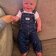 Harper joined the competition — help win amazing prizes! baby, child, denim_overalls, pink_hearts, couch, beige, smiling, holding_hand, indoor, cute, portrait, person, feet, short_sleeve_shirt, light, happy, infant, seated, hand, cozy