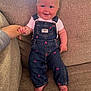 baby, child, denim_overalls, pink_hearts, couch, beige, smiling, holding_hand, indoor, cute, portrait, person, feet, short_sleeve_shirt, light, happy, infant, seated, hand, cozy