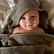 Adonis participe au concours pour gagner de l'argent avec cette photo : baby, infant, towel, hood, bear_ears, blanket, bed, smile, cheeks, eyes, portrait, close_up, soft_texture, fabric, cozy, bath_time, wrapped, cute, happy, skin