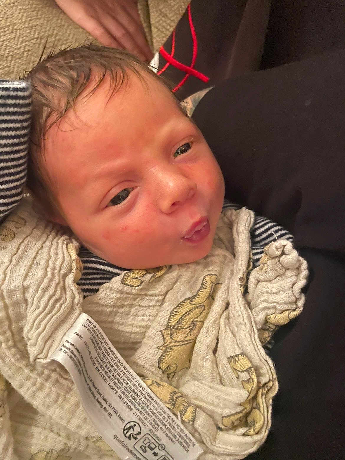 Christopher is registered to the contest to win money with this photo: baby, infant, face, expression, cloth, blanket, pattern, skin, hand, head, portrait, newborn, resting, closeup, person, curious, red_spots, fabric, sleepwear, indoors