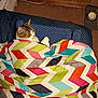 Taz is registered to the contest to win money with this photo: cat, blanket, cushion, indoor, pet, resting, colorful, patterned, carpet, food_bowl, wood_paneling, cozy, fur, relaxed, domestic, animal, comfort, sleepy, home, feline