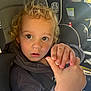 Hudson is registered to the contest to win money with this photo: child, toddler, car_seat, seatbelt, hand, curly_hair, hazel_eyes, close_up, portrait, hoodie, inside_car, sunlight, window, surprised_expression, face, mouth, nose, skin, young_child, seat