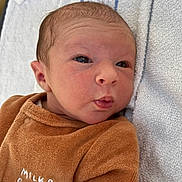 Chiara participe au concours pour gagner de l'argent avec cette photo : newborn, baby, infant, face, clothing, brown_outfit, towel, soft_texture, portrait, cute, small, lying_down, expression, indoors, child, young, person, sleepwear, cozy, closeup