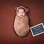 Liam joined the competition — help win amazing prizes! newborn, baby, sleeping, knitted_wrap, bear_ears, brown_background, portrait, infant, cute, cozy, soft_texture, chalkboard, birth_details, resting, child, wrapped, studio_photo, adorable, peaceful, small