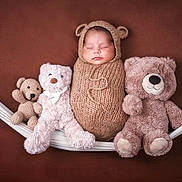 Liam joined the competition — help win amazing prizes! baby, swaddled, knit_outfit, bear_ears, hammock, teddy_bears, sleeping, cozy, brown_background, cute, soft_toys, infant, child, portrait, resting, adorable, plush, comfort, warm, peaceful
